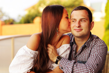 Beautiful girl kissing her boyfriend on the cheek