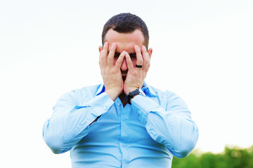 Stressed businessman covering his face with hands