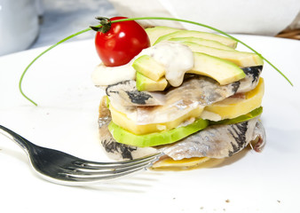 Herring salad with avocado sauce on a plate in a restaurant