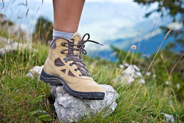Pied avec une chaussure de marche dans l'herbe en randonnée à la montagne