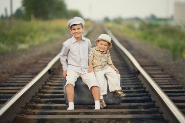 Two happy boys with suitcase on railways