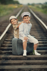 Two happy boys with suitcase on railways