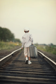 little boy with suitcase on railroad
