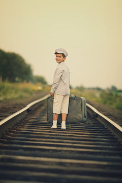 little boy with suitcase on railroad