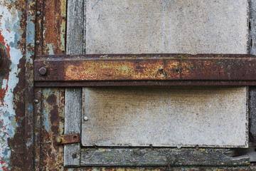 Old window closed with plywood and rusty girder
