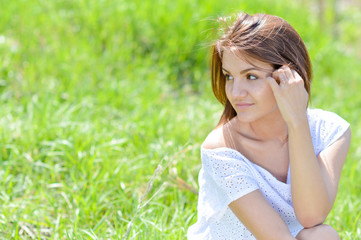 Naklejka na ściany i meble Happy young woman in short white summer dress on green grass