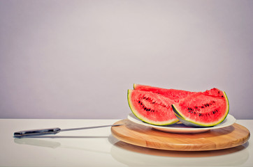 Slices of a green melon on a table and a big knife