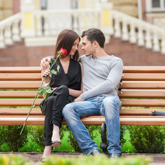 Loving couple on the bench. Cheerful young couple sitting close