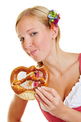 Frau im Dirndl kaut eine Brezel