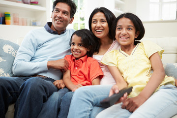 Obraz premium Indian Family Sitting On Sofa Watching TV Together