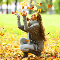 woman drop leaves in autumn park