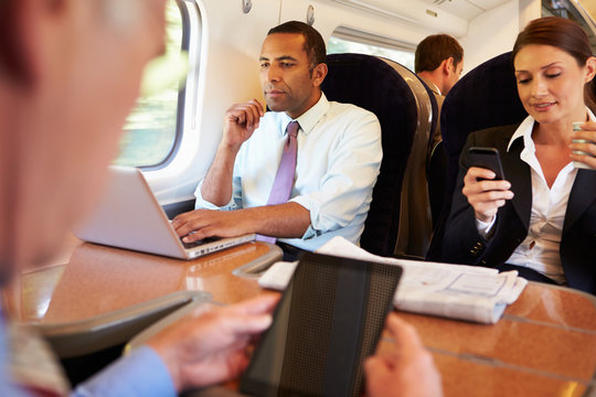 Businesspeople On Train Using Digital Devices