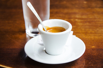 White espresso cup with glass of water on the wooden table