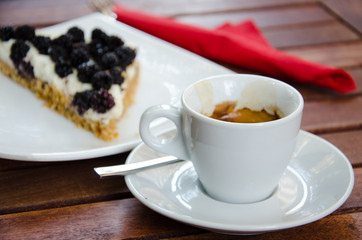 White espresso cup and a piece of blackberry cheesecake
