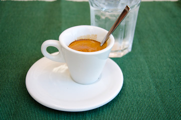 White espresso cup and a glass of water on the green table