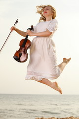 Happy blonde girl with a violin outdoor