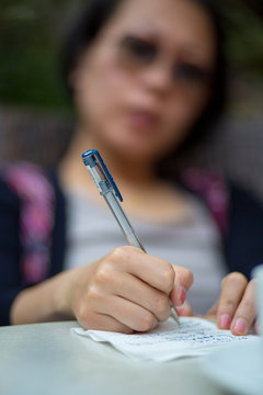 Close-up of a Chines woman writing a letter on a table.