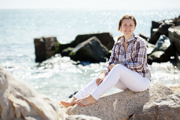 Fototapeta na wymiar woman sits on stone at sea