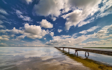 pier in large lake under blue sky and clouds