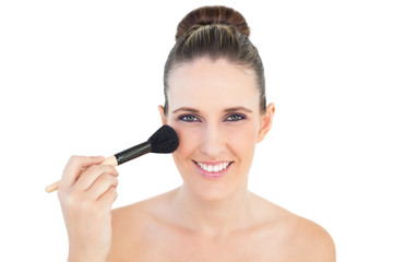 Fototapeta premium Portrait of delighted woman using blusher brush