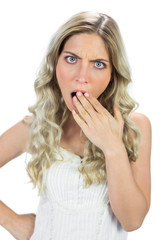 Shocked blond model hiding her mouth wide open
