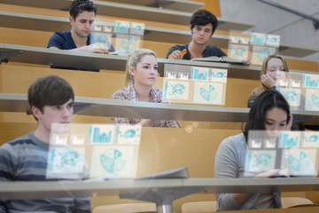 Focused students in lecture hall working on their futuristic tab