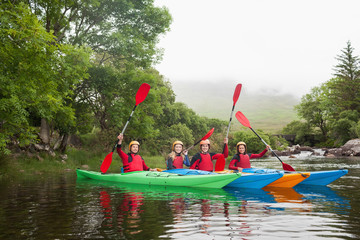 Friends kayaking together cheering at camera