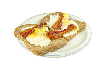 Two slices of brown bread with fried egg and bacon.
