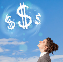 Young girl pointing at dollar sign clouds on blue sky