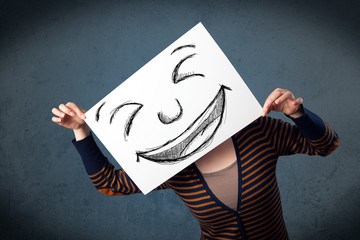 Woman with drawed smiley face on a paper in front of her head