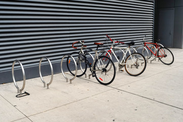 Fototapeta na wymiar 3 rowery są zablokowane do nowoczesnych szukających stojaki chodniku w Toronto