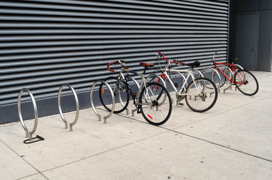 Fototapeta 3 bikes are locked to modern looking sidewalk racks in Toronto
