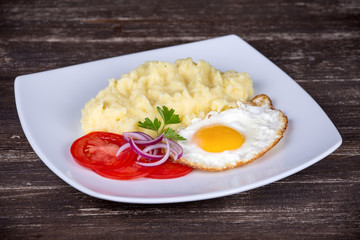 Mashed potatoes with fried eggs and tomato