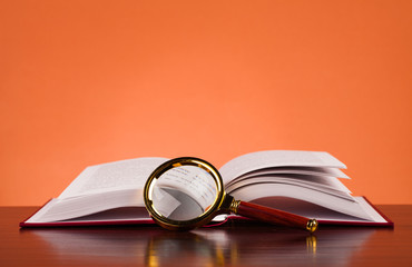 open book on wooden table and magifying glass