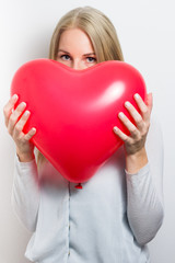 Woman hiding her face behind a red heart