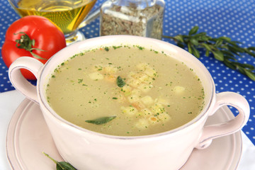 Nourishing soup in pink pan on blue tablecloth close-up