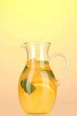 Orange lemonade in pitcher on yellow background