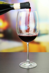 Red wine being poured into wine glass, on bright background