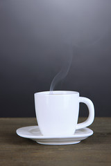 Cup of coffee on wooden table on black background