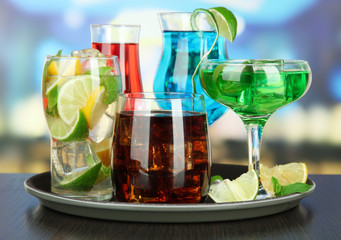 Many glasses of cocktails on tray on table, on bright