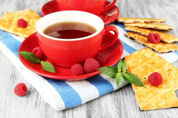 Cups of tea with cookies and raspberries on table close-up