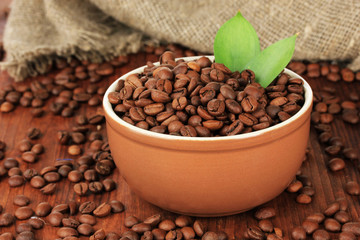 Coffee beans in bowl on wooden background
