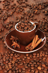 Coffee beans in cup on wooden background