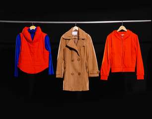 Three female dress, coat isolated on hanging-black background