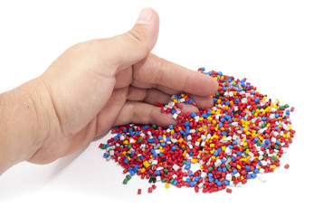 Colorful plastic polymer granules and man hand on white
