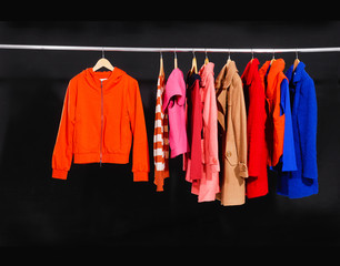 Set of colorful jacket, coat hanging on hanger-black background