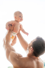 Man with baby. Young muscular man holding baby in his hands
