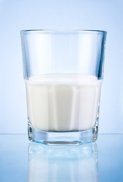 Half a glass of fresh milk isolated on blue background