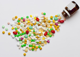 Many colorful medicines spilling out of a bottle.