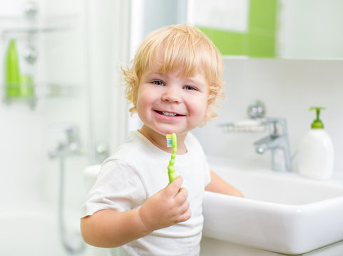 Happy Kid Or Child  Brushing Teeth In Bathroom. Dental Hygiene.